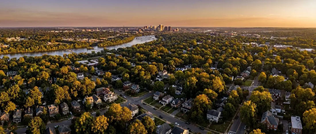 Illustration: aerial view over Richmond's leafy suburbs toward downtown and the James River at golden hour